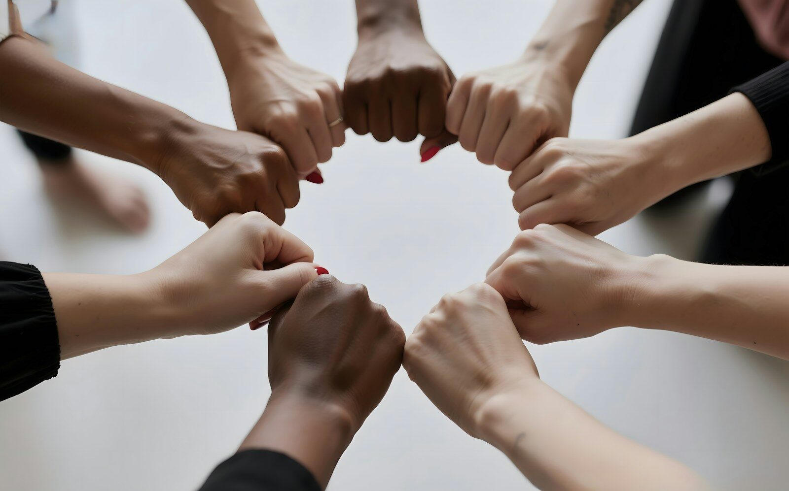 People of diverse skin tones fist bumping in a circle